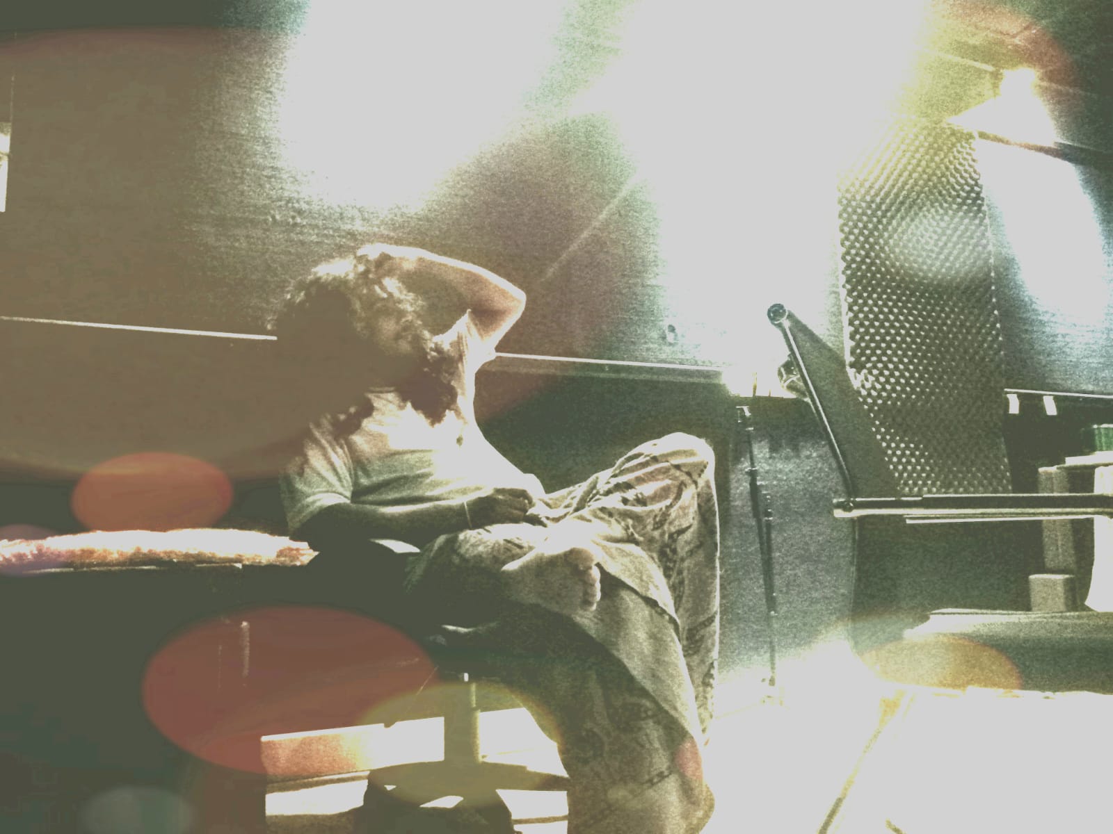 Chandana Dassanayake resting between takes in a warmly-lit studio, surrounded by acoustic gear
